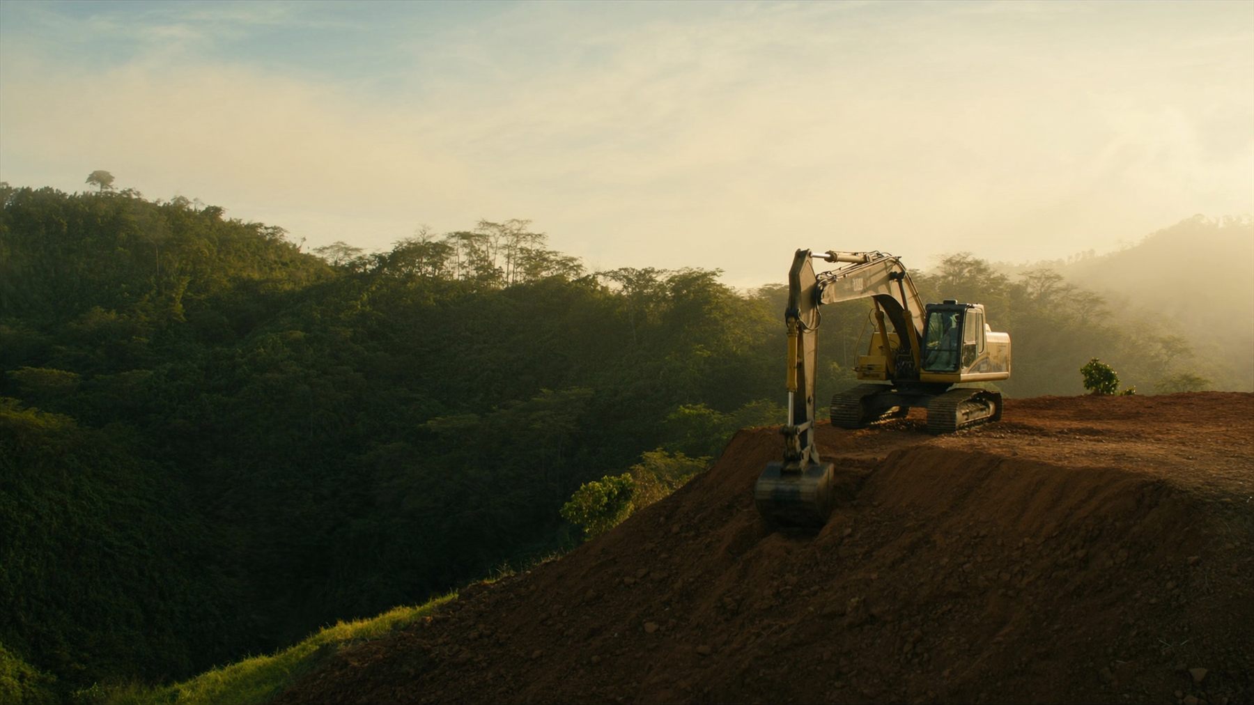 Excavadora de Genesis nivelando una plataforma en ladera